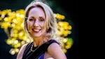 Hanneke Faber smiling in front of yellow flowers