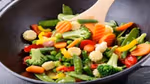 Wok pan with variety of colorful vegetables being stirred