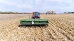 Red and green tractor driving through in a field of corn