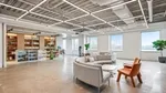 Unilever's company store with products on shelves, and a curved gray couch sitting area. The windows feature view of NYC skyline.